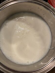 Heating milk to just under boiling point where small bubbles appear around the edge