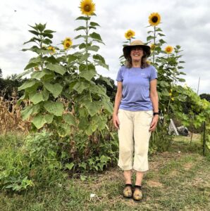 Nancy Dru staing in front of her pickles and sunflowers 2023.